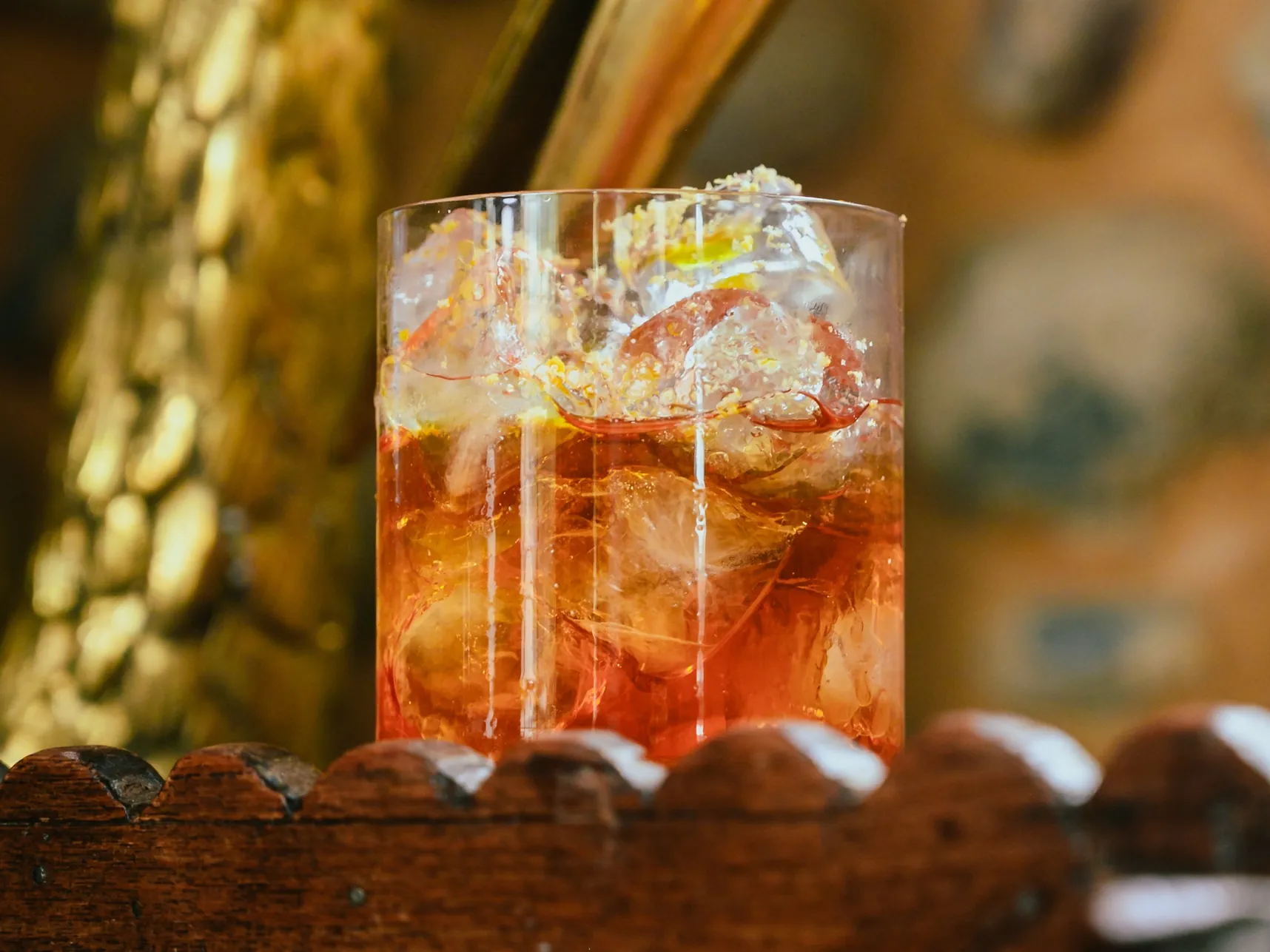 Golden Grapefruit Tonic in un bicchiere basso pieno di ghiaccio, con il bitter rosso che scende nel drink e una spolverata dorata sopra